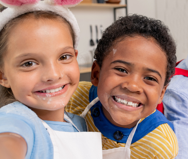 Two smiling children wearing dental bibs in a pediatric dental office setting.