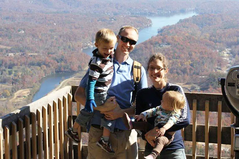 Family of four enjoying scenic overlook view from wooden observation tower.