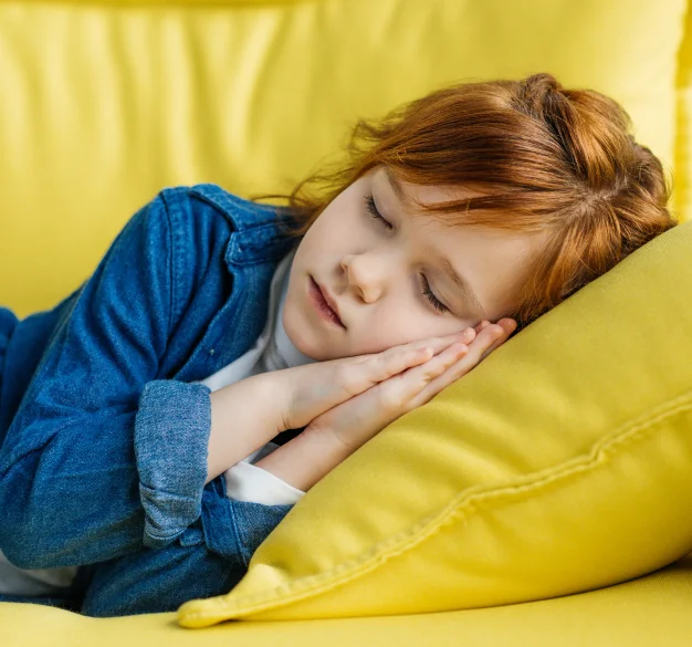Child sleeping peacefully on a yellow couch